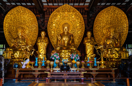 Golden sitting statues of Sakyamuni Buddha, Manjushri and Samantabhadra in Mahavira Hall in Baoshan or Treasure Mountain Serene Temple at Luodian Town, Baoshan, Shanghai, China. photo