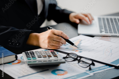 Fototapeta Naklejka Na Ścianę i Meble -  Close up of Businesswomen or Accountant using a laptop computer with analyzing business report graph and finance chart at the workplace, financial and investment concept