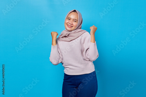 Portrait of excited asian woman celebrating success with raised arms