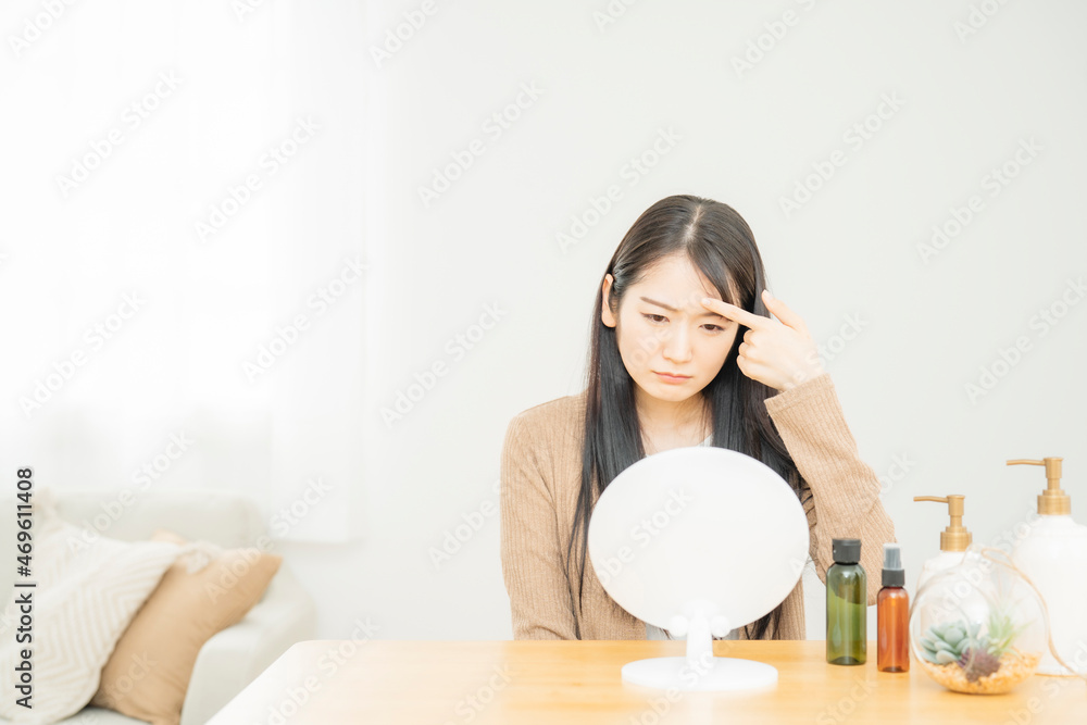 おでこを指差す女性（悩む）
