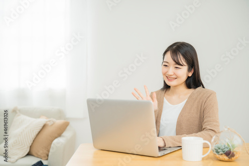 家でノートパソコンを使う女性（笑顔） 