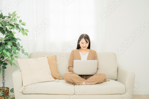 家でノートパソコンを使う女性（ソファ）  © buritora