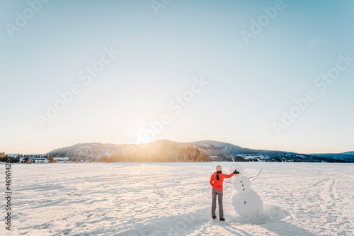 Winter activity. Woman making snowman in winter lake snow nature landscape