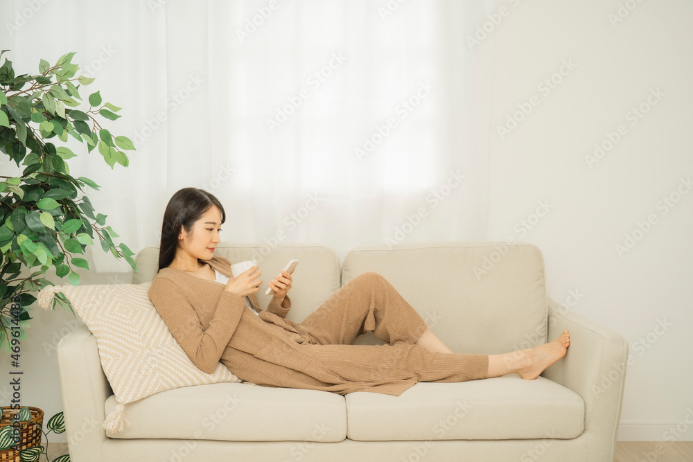 ソファでスマホを使う女性(笑顔)
ソファでスマホを使う女性(笑顔)