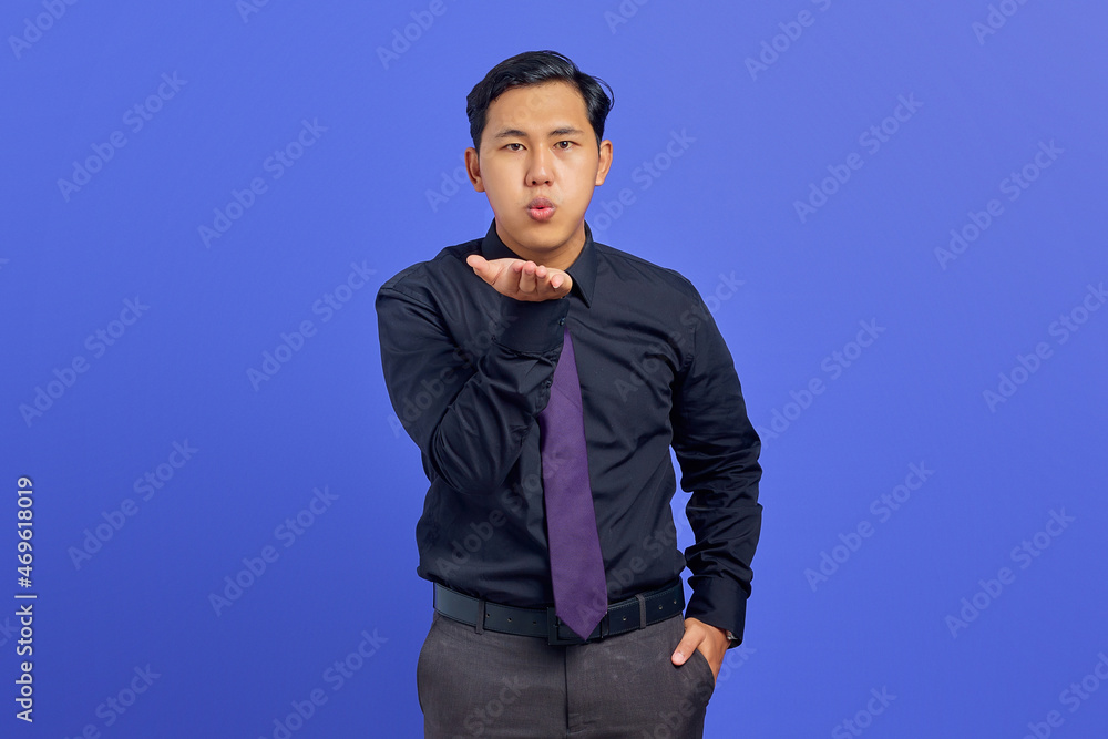 Portrait of charming young Asian man hold hand palms send air kiss on purple background Portrait of charming young Asian man hold hand palms send air kiss on purple background