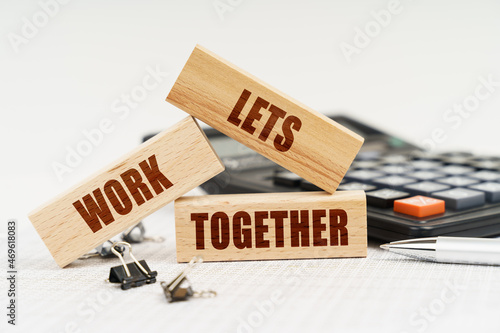 On the table is a pen, a calculator and small wooden blocks with the inscription - Lets Work Together photo