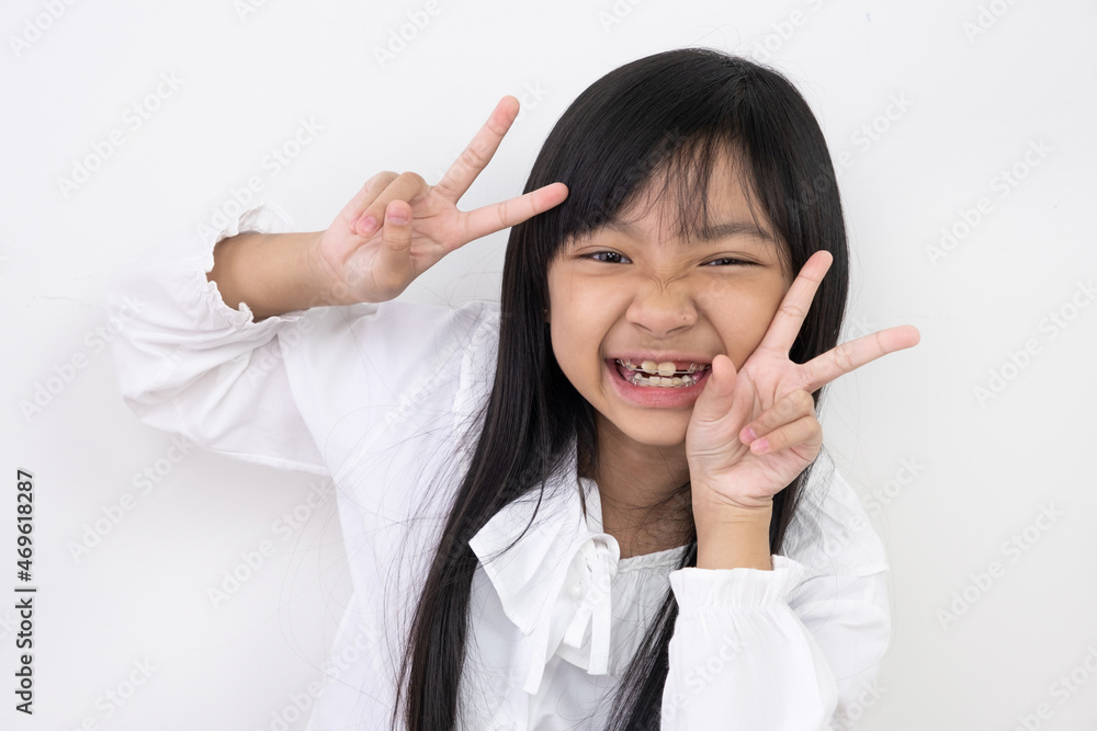 Asian girls wearing white shirt smiling and holding two fingers in a good mood on white background Asian girls wearing white shirt smiling and holding two fingers in a good mood on white background