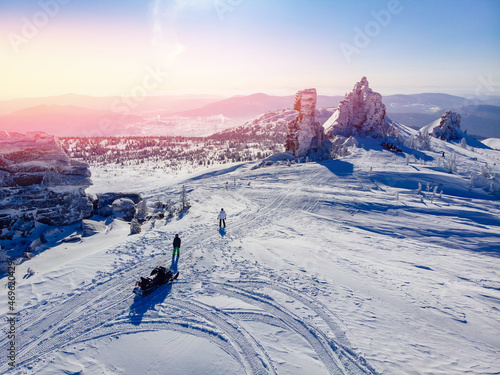 Concept travel tourist group snowmobile tour in frozen forest. Polar arctic snow mountains with sun light, aerial top view