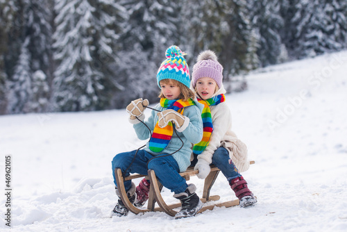 Children on sleigh. Kids boy and girl plays outside in the snow. Winter, holiday and Christmas time. New Year wallpaper, Christmas greeting card.