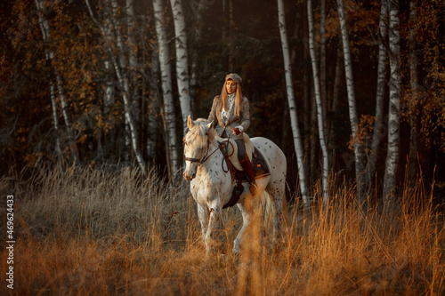 Beautiful young woman in English hunter wear style with Knabstrupper horse and Irish setter at autumn park © Julia Shepeleva