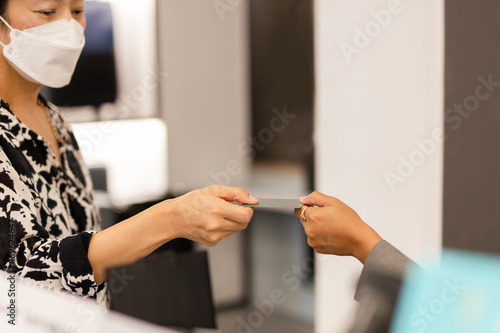 Female customer in protective mask paying shopping by credit card.