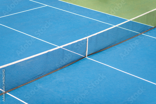 Top view of a tennis court with blue floor and black netting