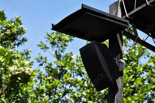 Mini speaker of the outdoor stage installed on the black metal pole which has metal roof above to protect it from the rain.