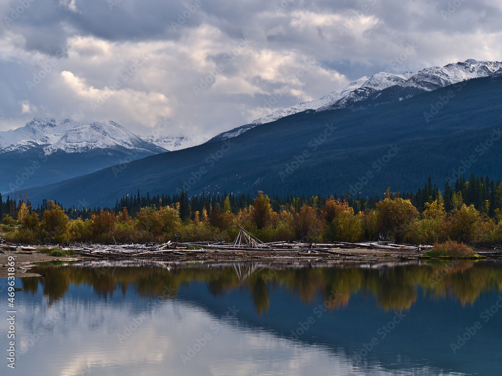 View of the southern shore of Moose Lake in Mount Robson Provincial Park, British Columbia, Canada with colorful trees reflected in the water.