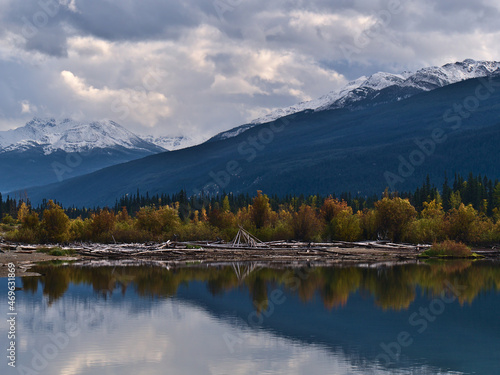 View of the southern shore of Moose Lake in Mount Robson Provincial Park, British Columbia, Canada with colorful trees reflected in the water.