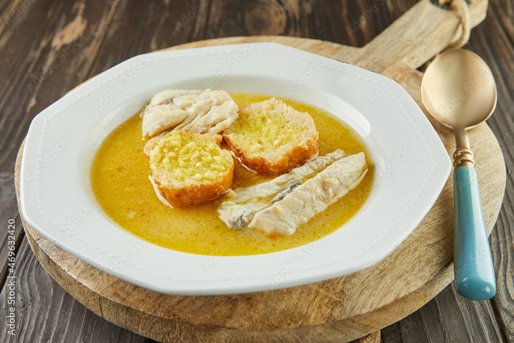 White Fish Soup - Buried with baguette, in white plate on wooden board. French gourmet cuisine