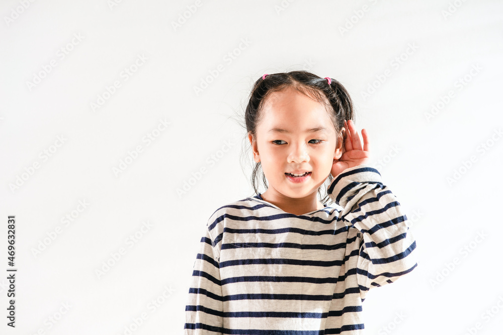Happy Positive cute Asian little toddler kid girl holding ear with hand listening to a hearing for rumor or gossip. Over white background for text copy and space. Deafness concept Happy Positive cute Asian little toddler kid girl holding ear with hand listening to a hearing for rumor or gossip. Over white background for text copy and space. Deafness concept