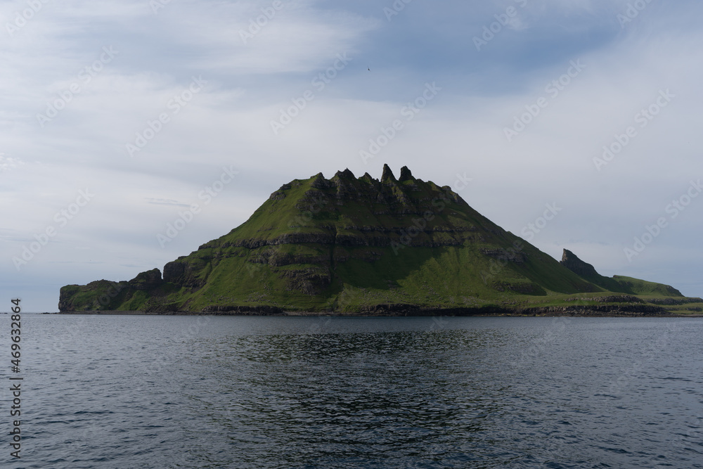 View of the impressive Rocky Drangarnir sea stack and the fishing farms in the Faroe Islands seen from the ferry to Mykines 