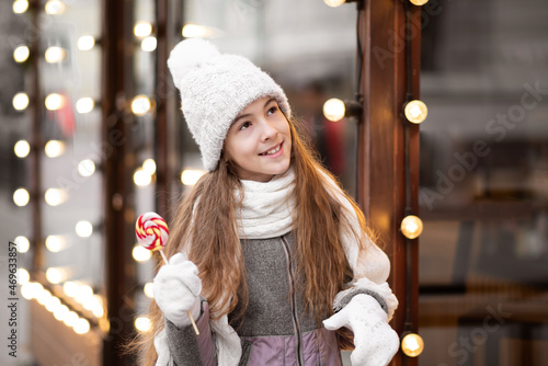 Fotografía A beautiful smiling girl with candy walks on the city