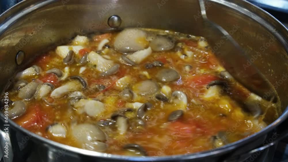 Soup preparation. A spoon to stir the tomato veggie soup with mushrooms. Recipe and cooking concepts Soup preparation. A spoon to stir the tomato veggie soup with mushrooms. Recipe and cooking concepts