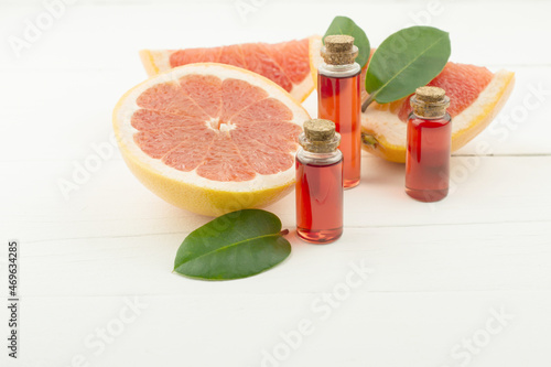 the concept of natural organic grapefruit essential oil for self-care. Grapefruit essence in bottles on a white background with fruits.
