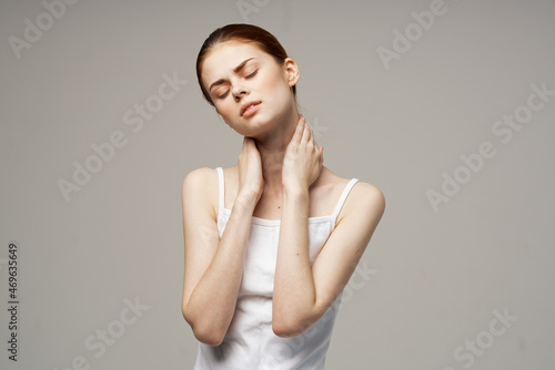 woman in white t-shirt holding on to the neck health problems joint light background