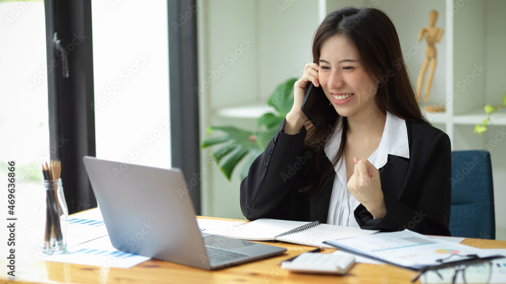 A happy female employee received great news from her phone call. A happy female employee received great news from her phone call.