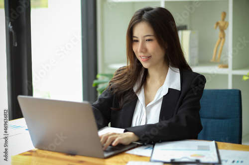 Successful businesswoman in formal suit working on laptop.