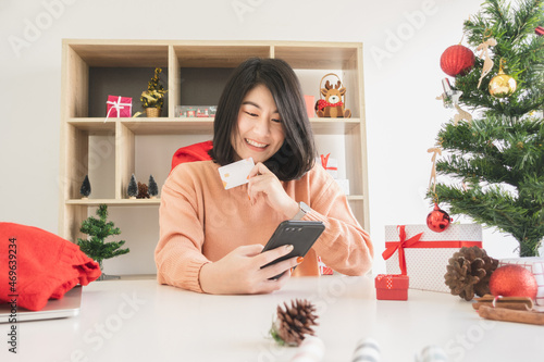 young asian woman using mobile phone and holding credit card for christmas online shopping