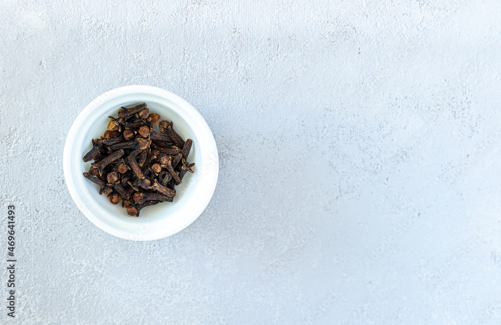 Dry cloves spices in white plate isolated on gray background. High quality photo