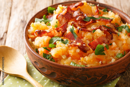 Mashed potatoes and carrots with bacon close-up in a bowl on the table. horizontal photo