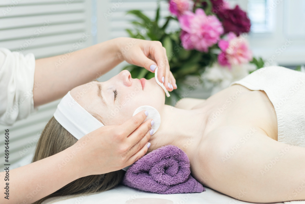 Beautiful young woman at reception at beautician. Facial cleansing at beauty spa salon. Side view. Beautiful young woman at reception at beautician. Facial cleansing at beauty spa salon. Side view.