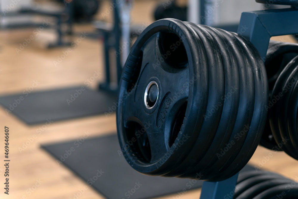 Obraz premium Black dumbbells for barbells. Equipment for weight gain. Sports equipment. Different weights for the barbell.