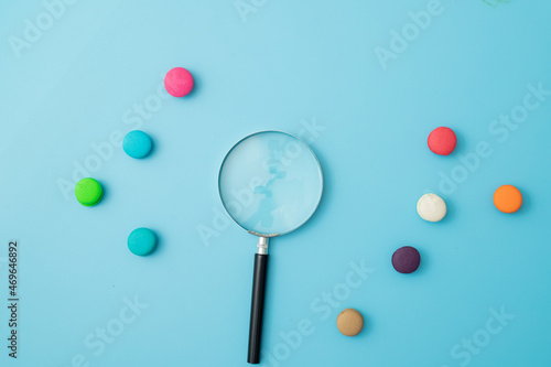 information search concept Magnifying glass with colorful candy on a blue background 