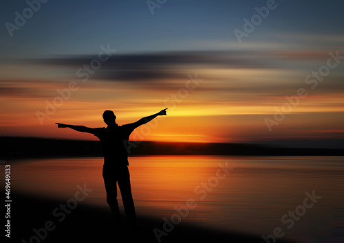 Sunset silhouette of a man with out stretched on the beach 