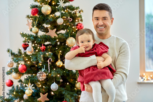 winter holidays and family concept - happy middle-aged father and baby daughter over christmas tree at home