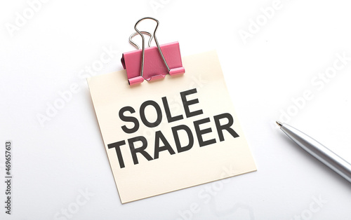 SOLE TRADER text on the sticker with pen on white background
