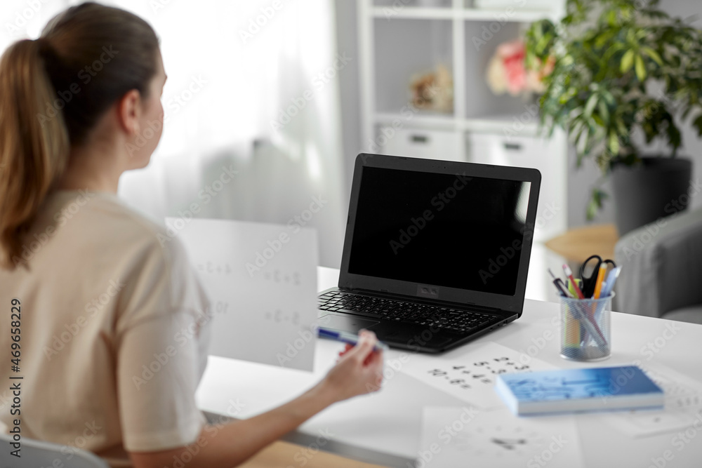 distant education, school and people concept - female math teacher with laptop computer and mathematics having online class at home distant education, school and people concept - female math teacher with laptop computer and mathematics having online class at home