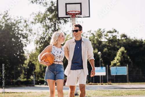 sport, love and people concept - happy young couple with ball on basketball playground © Syda Productions