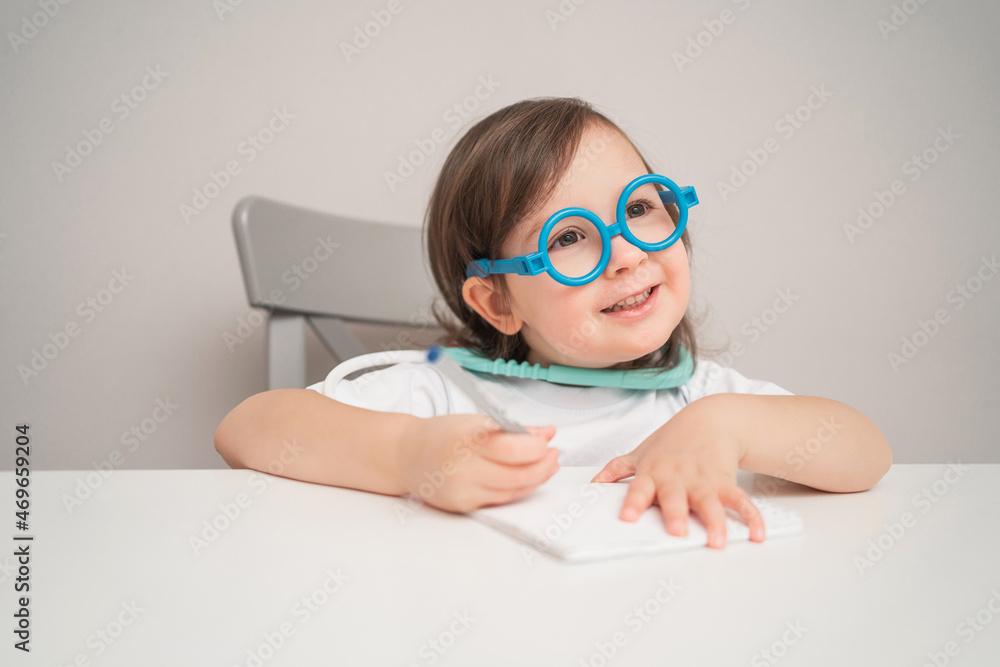 A small child in a doctor's costume. An artistic girl plays doctor. A child in glasses and a white T-shirt. A small child in a doctor's costume. An artistic girl plays doctor. A child in glasses and a white T-shirt.