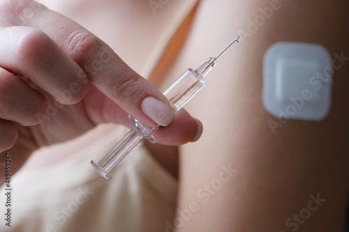 Woman holding syringe filled with medicine liquid and patch on arm