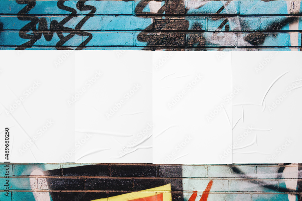 Closeup of colorful messy painted urban wall texture with four wrinkled glued poster templates. Modern mockup for design presentation with clipping path. Creative urban city background.  - obrazy, fototapety, plakaty 