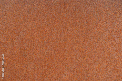 Rusty metal sheet with uniform orange corrosion in uniform lighting. Background