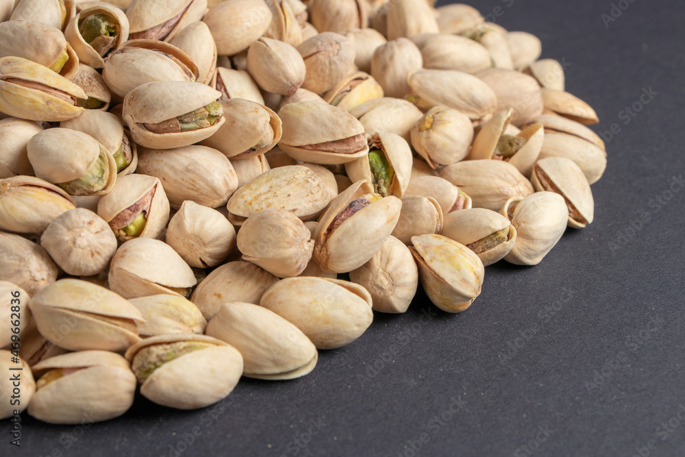 Pile of pistachios in the peel close-up on a dark background. Pile of pistachios in the peel close-up on a dark background.