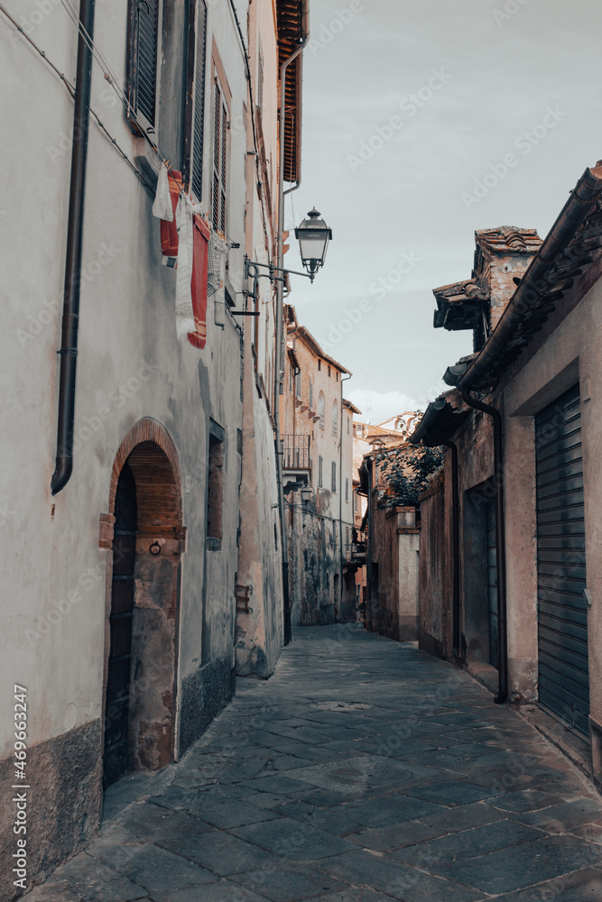 Glimpse of a medieval city. Old houses with ocher walls lined up. Concept of vacation in Italy. Vertical image. Photographed in Monte San Savino, Tuscany, Italy.