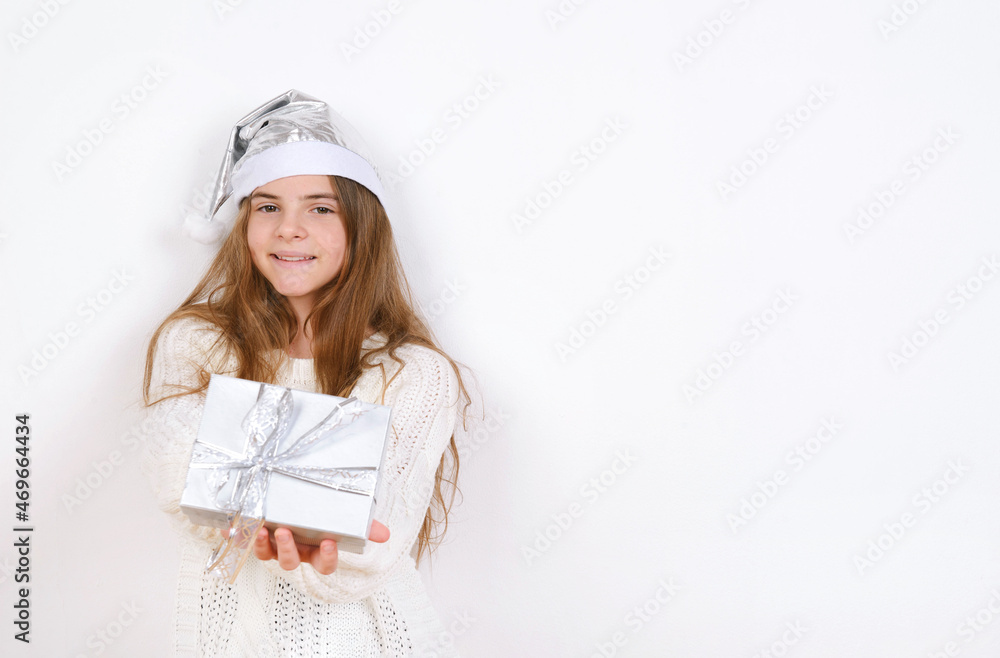 Young girl in white sweater and silver santa hat holds present christmas smile Young girl in white sweater and silver santa hat holds present christmas smile
