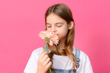 white teen girl with long hair in a white shirt with a flower on a pink background