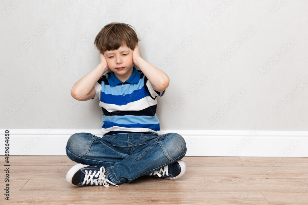 Child boy is sitting at home covering his ears. Generation gap, domestic violence concept