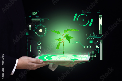 biotechnology science and medicine background, hands hold a tablet with a picture of green light plants and digital laboratory research photo