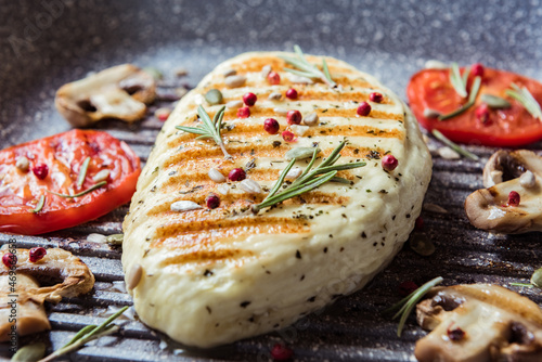 Cyprus fried halloumi cheese with red tomatoes, rosemary and champignons, close up. Balanced food. Cooking on grill pan photo